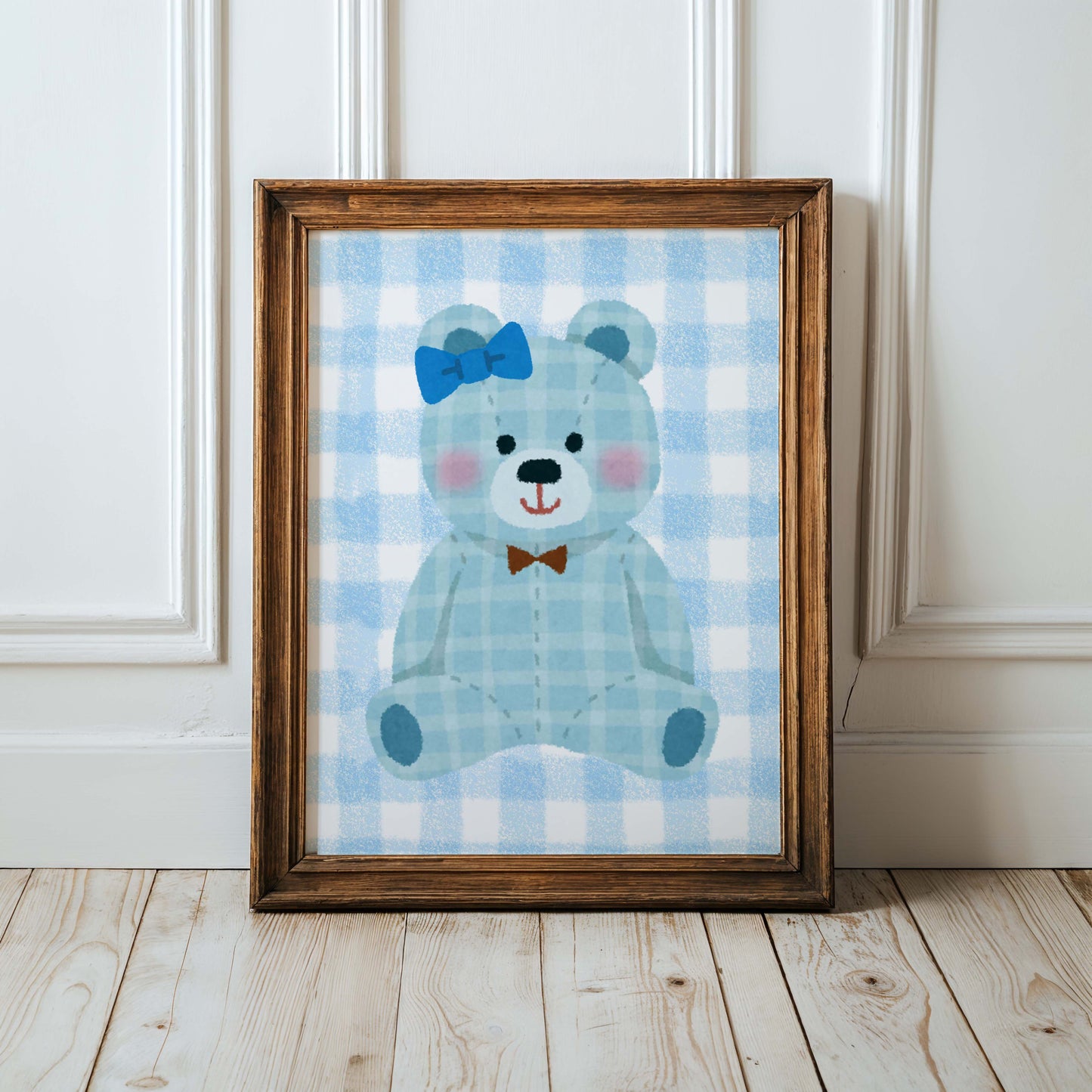 Blue gingham teddy bear nursery wall art print in a wooden frame, perfect for baby boy room decor. Features a cute teddy with a blue bow and a brown bow tie on a checkered background.